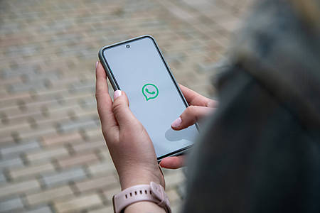 Smartphone mit WhatsApp Icon wird in der Hand gehalten