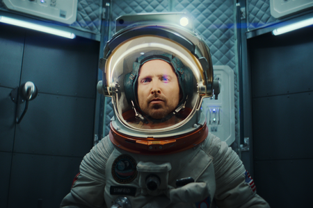Aaron Paul in seiner Rolle als Astronaut bei Black Mirror trägt in einer engen Kapsel einen Raumanzug.