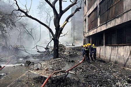 Ajit Solanki/AP/dpa | Feuerwehrleute arbeiten an der Absturzstelle.