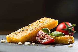 Franziska Gabbert/dpa-tmn | Wer keinen Polenta-Brei mag, kann daraus auch Schnitten machen. Einfach breit streichen, abkühlen lassen und braten. Dazu passen Tomaten, Feta und Basilikum. 