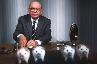 picture alliance / dpa | «Welches Schweinderl hätten Sie denn gern?»: Quizmaster Robert Lembke 1985 mit den berühmten «Was bin ich?»-Sparschweinen. 