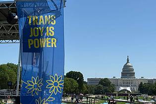 Franziska Spiecker/dpa | ?Trans joy is power? steht auf einem Banner an einer Bühne vor dem Kapitol am ersten Tag der Worldpride. 
