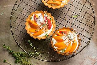 Manuela Rüther/dpa-tmn | Aromatisch und schön anzuschauen: Auf cremegefüllten Tartelettes macht sich ein Belag aus Aprikosenspalten sehr gut.