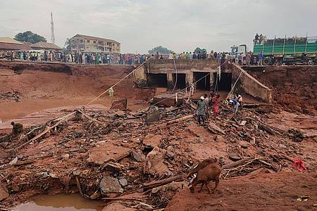 Chenemi Bamaiyi/AP/dpa | Menschen suchen in Mokwa noch Opfern der durch stundenlangen Regen ausgelösten Flut.