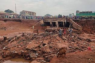 Chenemi Bamaiyi/AP/dpa | Menschen suchen in Mokwa noch Opfern der durch stundenlangen Regen ausgelösten Flut.