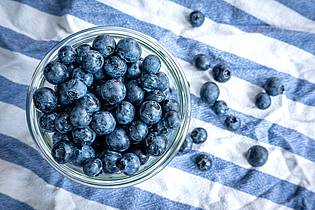Sina Schuldt/dpa | Beeren statt Chips oder Nüsschen: Heidelbeeren, auch Blaubeeren genannt, liegen auf einem Esstisch und werden gern gesnackt.
