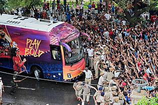 Aijaz Rahi/AP/dpa | Kricket-Fans in Bengaluru jubeln ihrem Heimteam zu, das in einem Bus sitzt.
