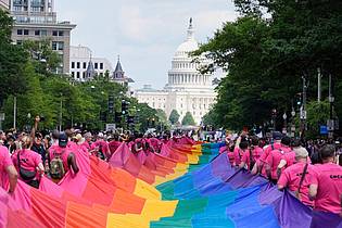 Mark Schiefelbein/AP/dpa | Mit riesigen Regenbogenfahnen demonstrieren Menschen mit Blick auf das US-Kapitol bei einer Pride-Parade in Washington für die Rechte der LGBTQI+-Gemeinschaft. 