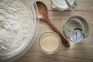 Christin Klose/dpa-tmn | Die Zutaten fürs Sauerteigbrot bestehen eigentlich nur aus Mehl und Wasser. Falls vorhanden, kommt auch Sauerteigansatz (Anstellgut) und je nach Rezept etwas Salz und Hefe hinzu. 