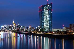 Die Lichter der Frankfurter Bankenskyline und der Europäischen Zentralbank (EZB) spiegeln sich im Main. Foto: Boris Roessler/dpa