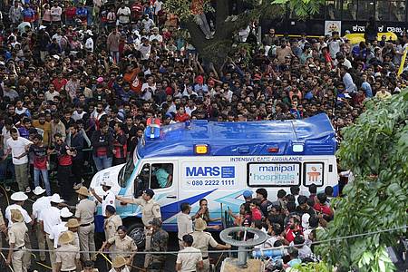 Aijaz Rahi/AP/dpa | Ein Krankenwagen bahnt sich den Weg durch eine Menschenmenge am M. Chinnaswamy-Stadion in der indischen Stadt Bengaluru. 