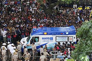 Aijaz Rahi/AP/dpa | Ein Krankenwagen bahnt sich den Weg durch eine Menschenmenge am M. Chinnaswamy-Stadion in der indischen Stadt Bengaluru. 