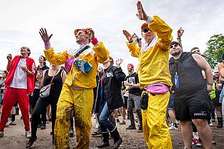 Daniel Karmann/dpa | Nach dem vielen Regen tanzten viele Fans im Matsch.