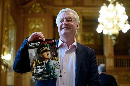 Hendrik Schmidt/dpa | «Compact»-Chefredakteur Jürgen Elsässer hält im Bundesverwaltungsgericht in Leipzig eine Ausgabe seines Magazins «Compact Geschichte» in der Hand. (Archivbild) 