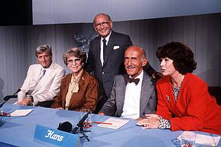 picture alliance / dpa | Quizmaster Robert Lembke (stehend) 1988 mit seinem Rateteam (von links nach rechts): Guido Baumann, Annette von Arentin, Hans Sachs und Marianne Koch.