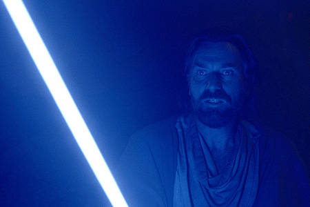 Obi-Wan Kenobi steht in der Dunkelheit, sein Gesicht von seinem Lichtschwert erleuchtet