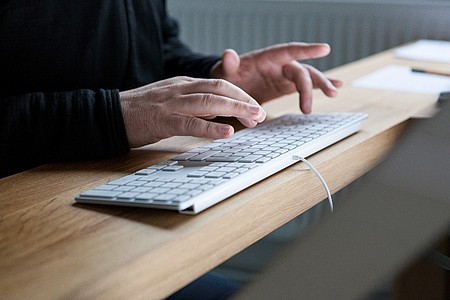 Mann tippt auf einer PC-Tastatur