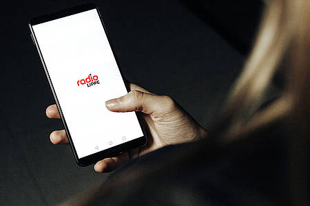 Frau hält Smartphone mit geöffneter Radio Lippe-App